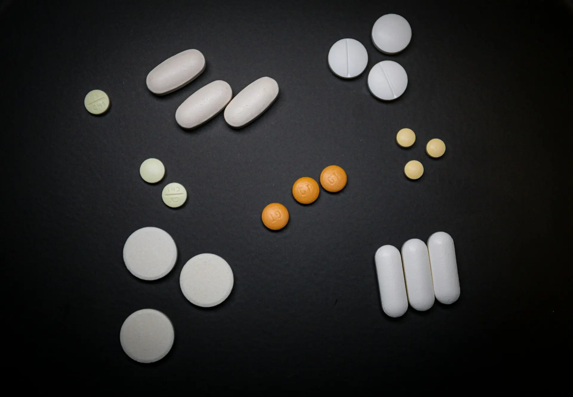 white and orange medication pill on black surface